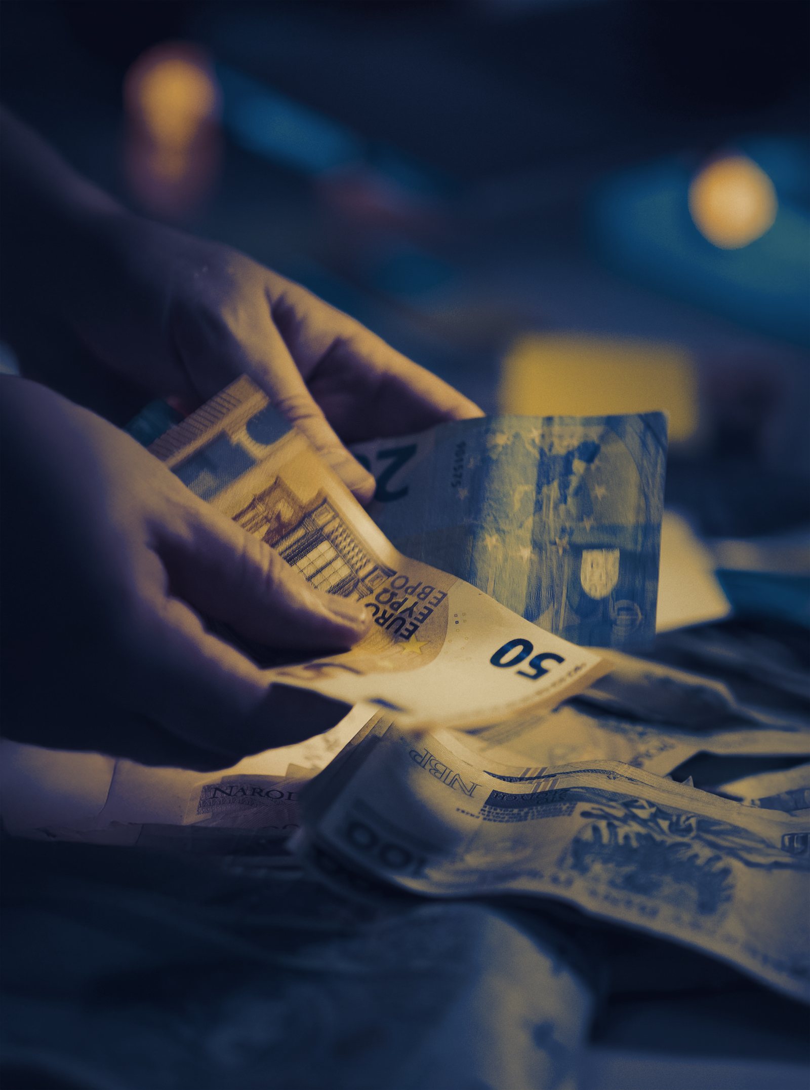 Hands counting euro notes over several other currencies